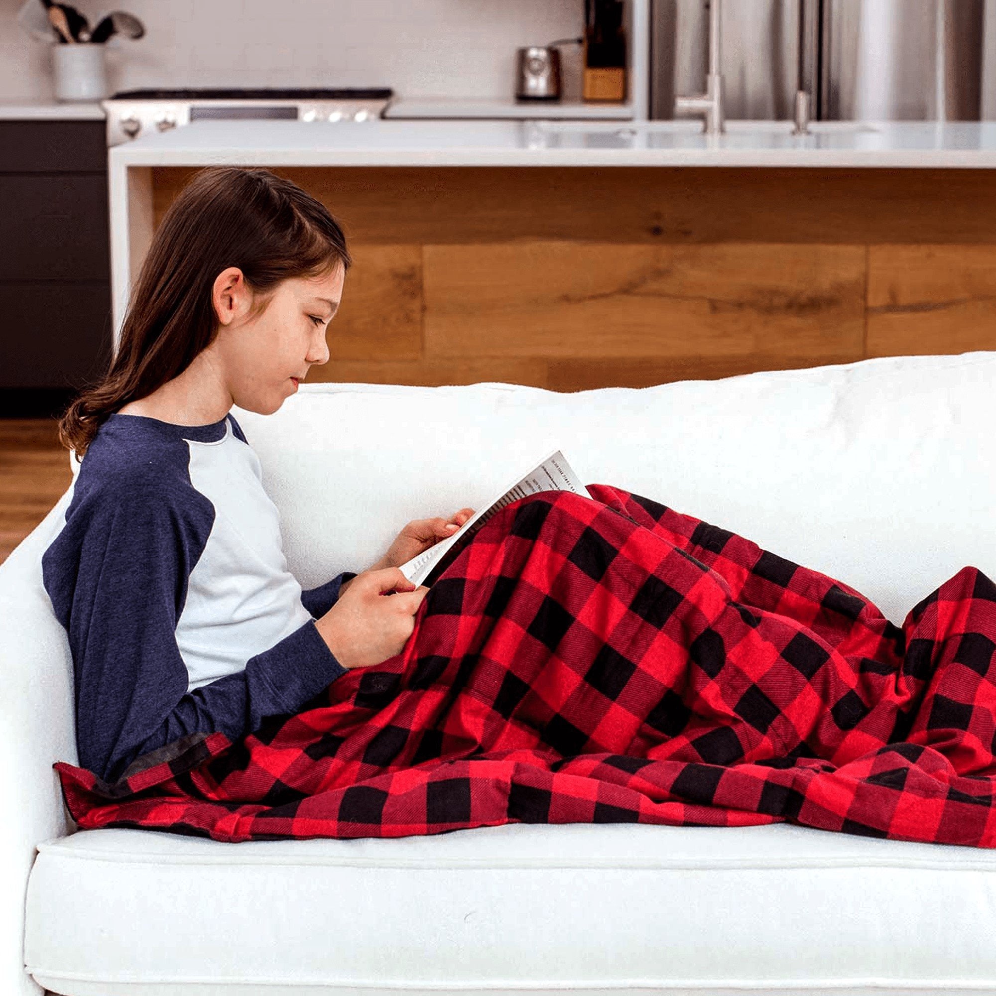 Child Reading And Sitting Under her Red And Black Plaid Weighted Blanket